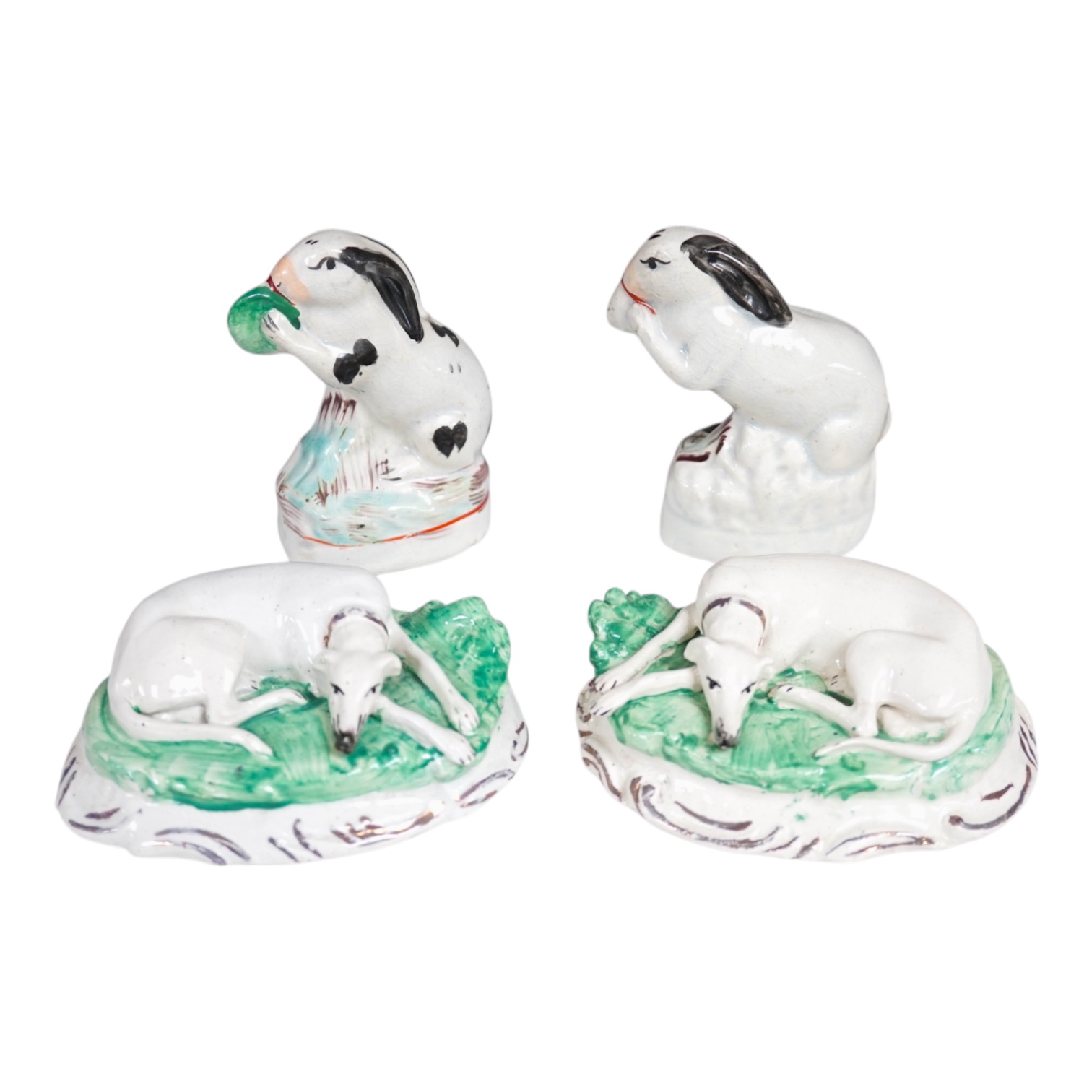 A pair of mid 19th century Staffordshire figures of recumbent greyhounds, 11 cm wide and a pair of similar groups of rabbits, 9.5cm high (4). Condition – fair to good